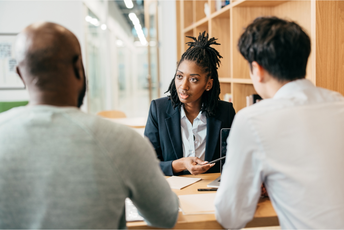 Woman seated at a table talking with 2 men